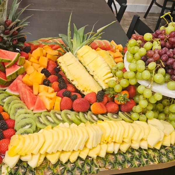 A large platter of fresh, colorful fruit, including pineapple, watermelon, kiwi, strawberries, and grapes.