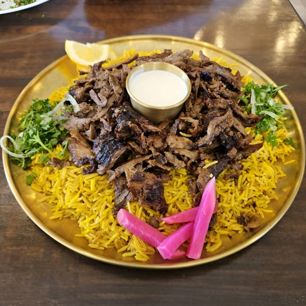 Tarbosh Mediterranean Restaurant's shawarma plate with yellow rice, meat, white sauce, lemon, and pickles.