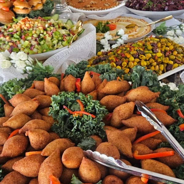 A buffet spread featuring kibbeh, hummus, olives, salad, and mini sliders at Tarbosh Mediterranean Restaurant.